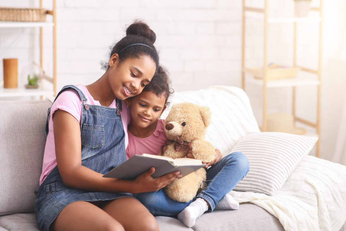 Two sisters reading fairy tale at home