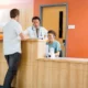 Doctor and nurse working at reception desk while patient standing in hospital