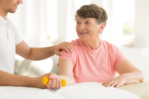 elderly woman working out with the help of a trainer