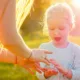 little girl applying sunscreen in a field