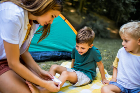 mom putting a bandage on her son's skid knee